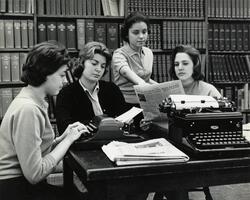 Students in library with typewriters, newspapers