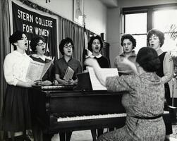 Students singing at piano with instructor