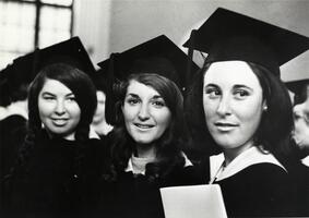 Three graduates in caps, gowns at Commencement