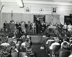 President Samuel Belkin addressing students in auditorium.  Founder Max Stern, faculty, also pictured