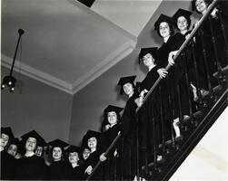 Students of first graduating class on stairs in caps and gowns