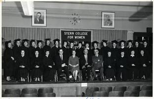 Students of first graduating class on stage in caps and gowns at commencement rehearsal