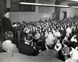 President Samuel Belkin addressing students in auditorium.