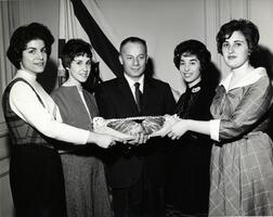 Students presenting hamentaschen to unidentified man at Purim event
