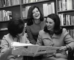 Three students in library reading Yeshiva College student newspaper The Commentator