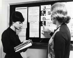 Students reading item on bulletin board