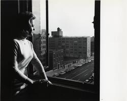 Student looking out of window on uptown campus buildings